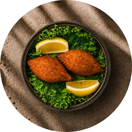 Bulgur Bites — Zwei frittierte Bulgurhüllen mit Rinderhack, dazu Zitrone.